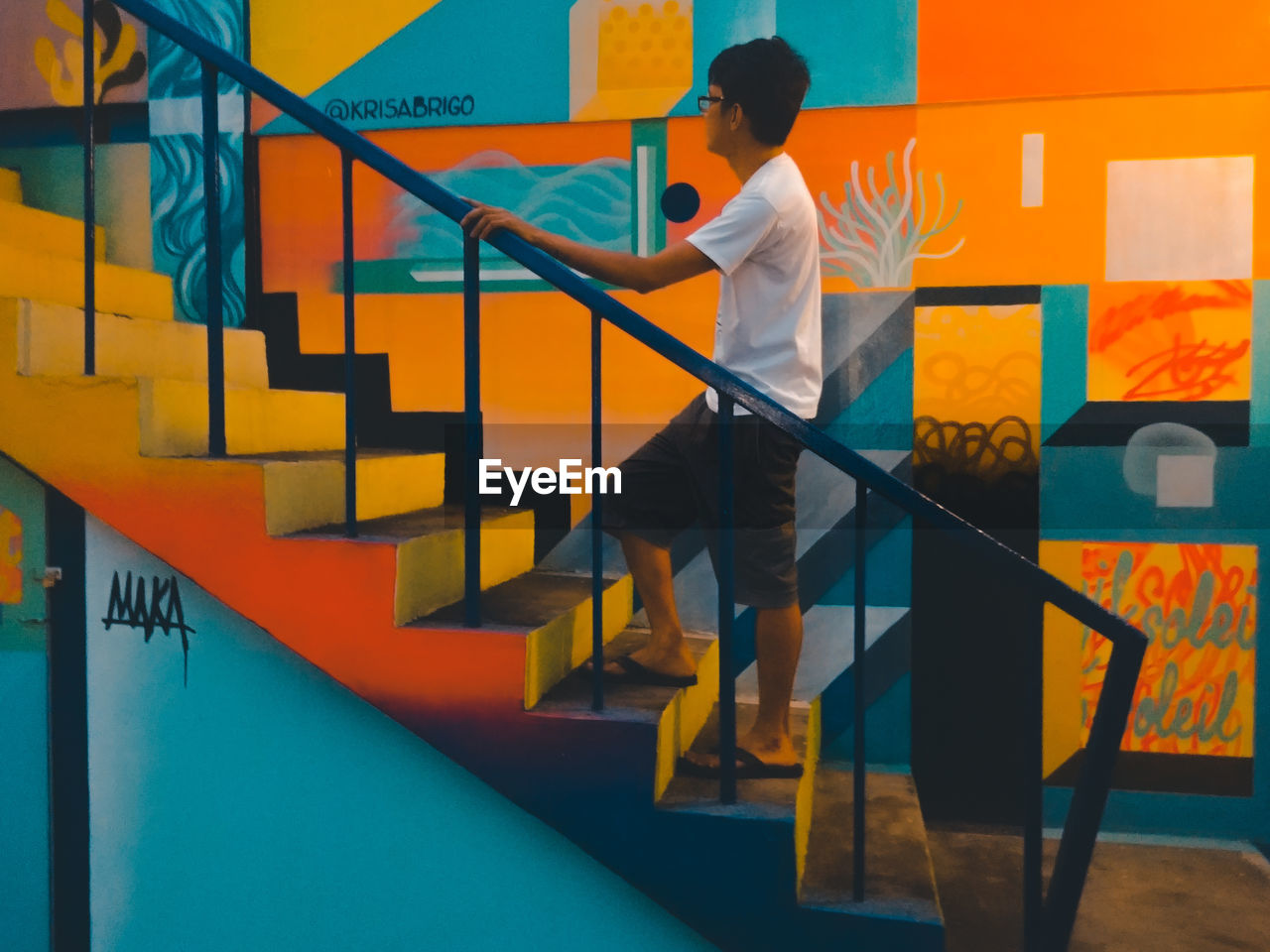 Side view of man climbing stairs by painted wall