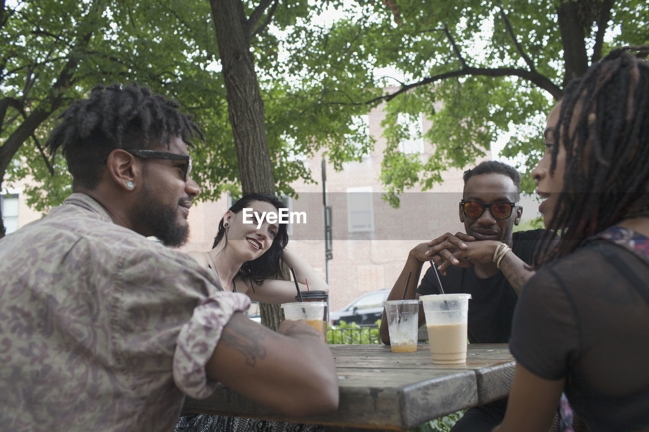 A group of friends having a conversation at a picnic table.