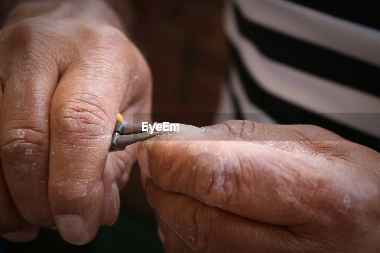 Cropped hands on man turning wire with tweezers