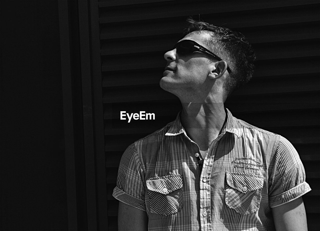 Close-up of man wearing sunglasses against black background