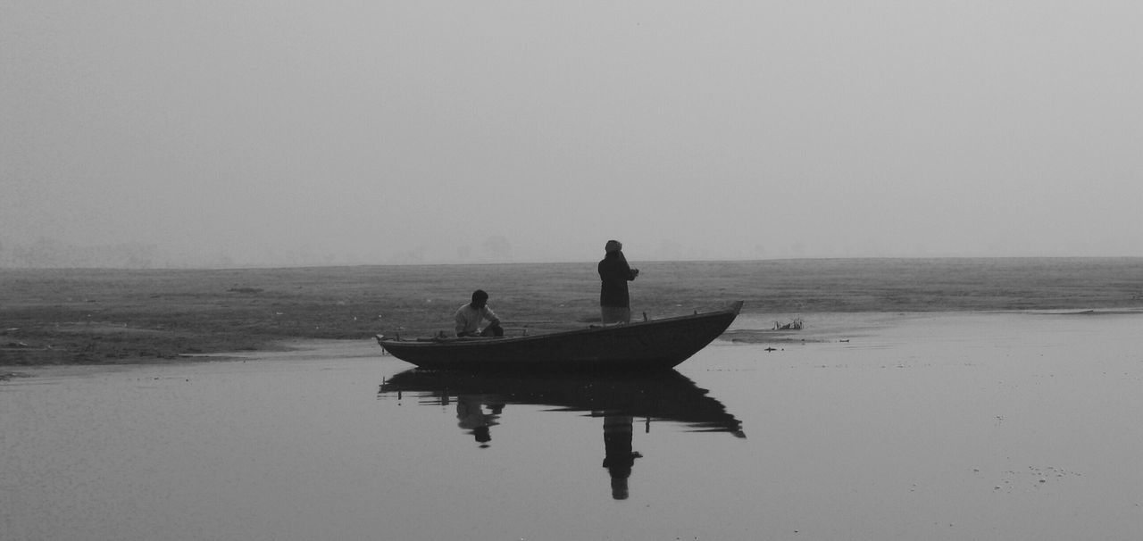 People sailing boat in lake against sky