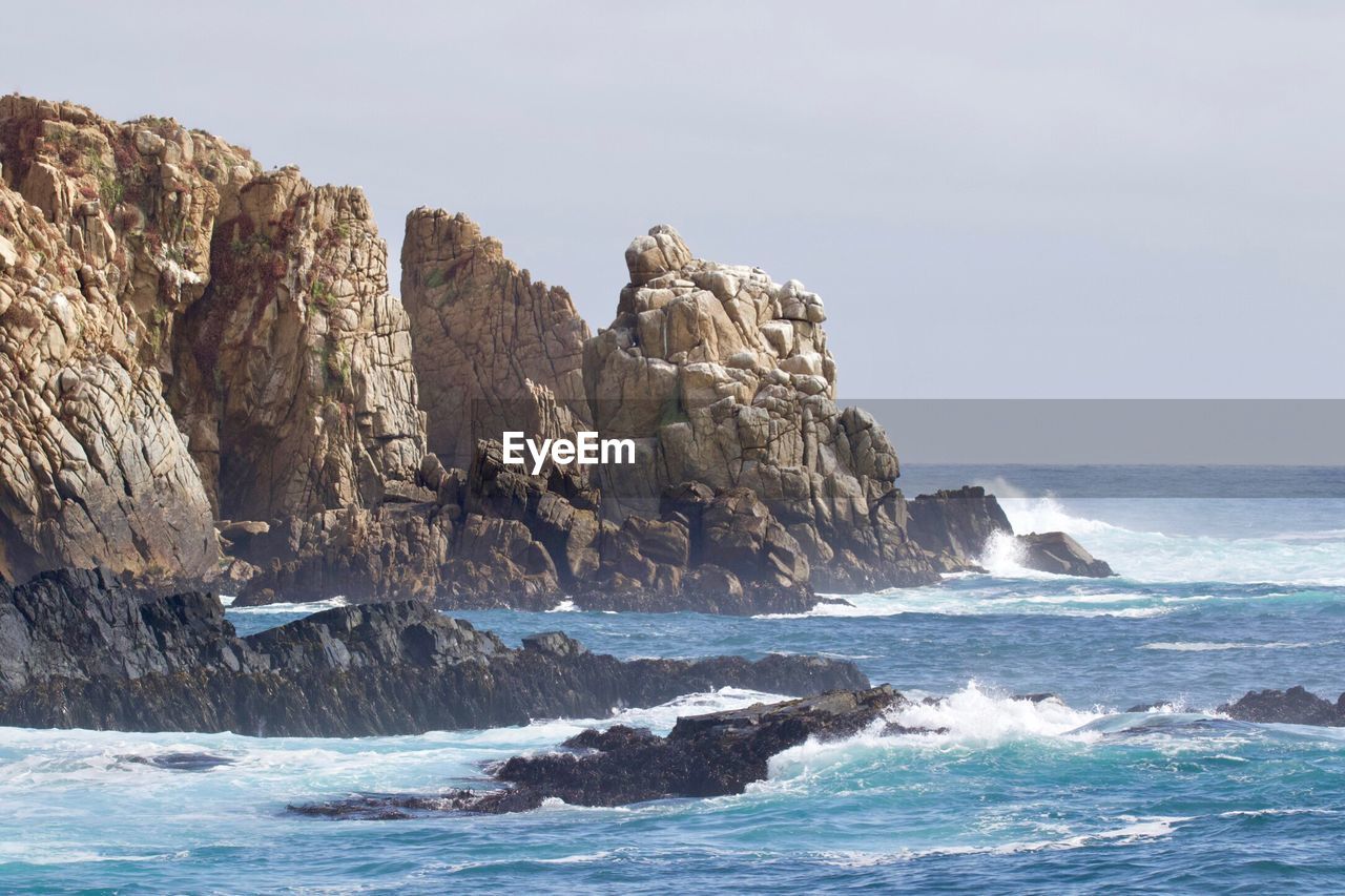 Rock formation in sea against clear sky