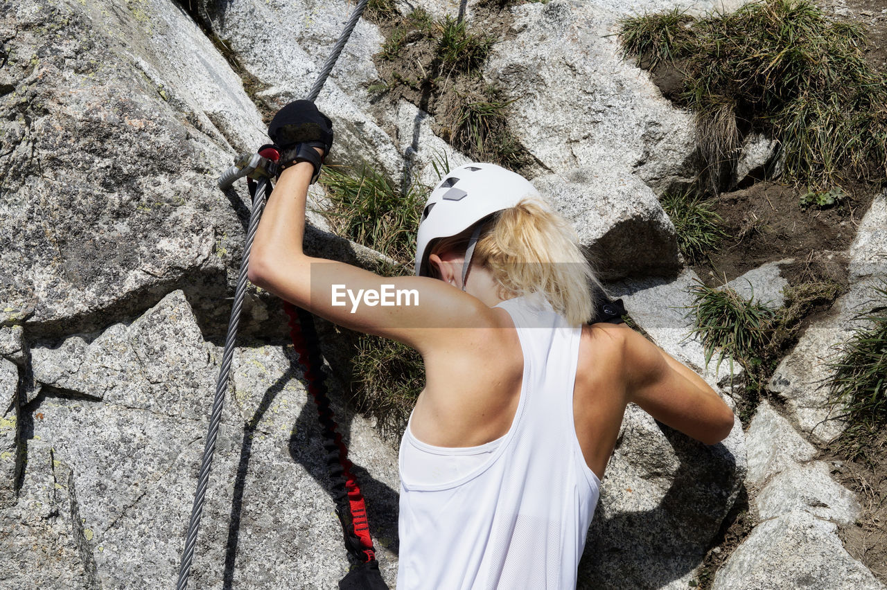 Rear view of young woman climbing rock
