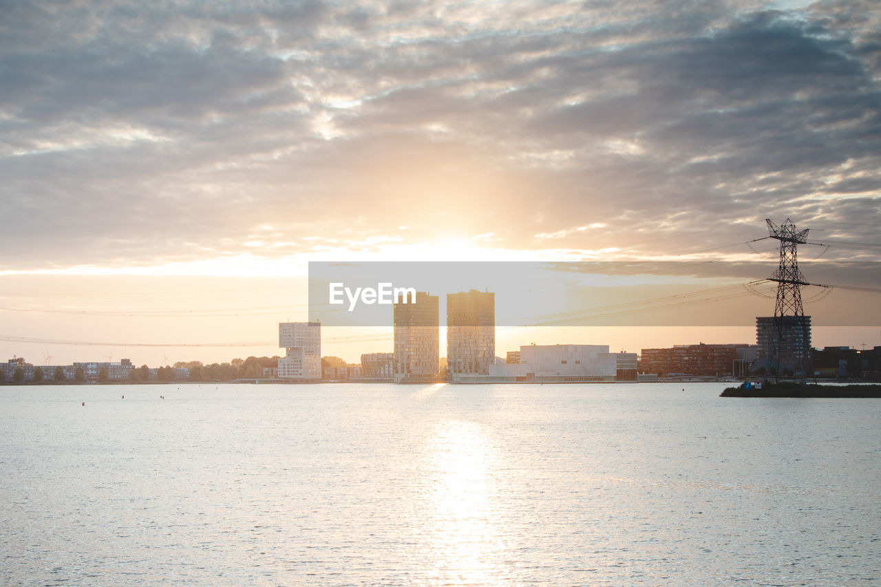 scenic view of sea by buildings against sky during sunset