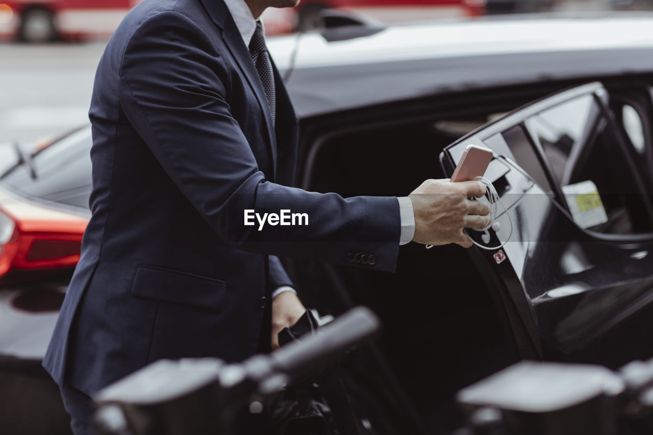 Midsection of businessman with smart phone sitting in car