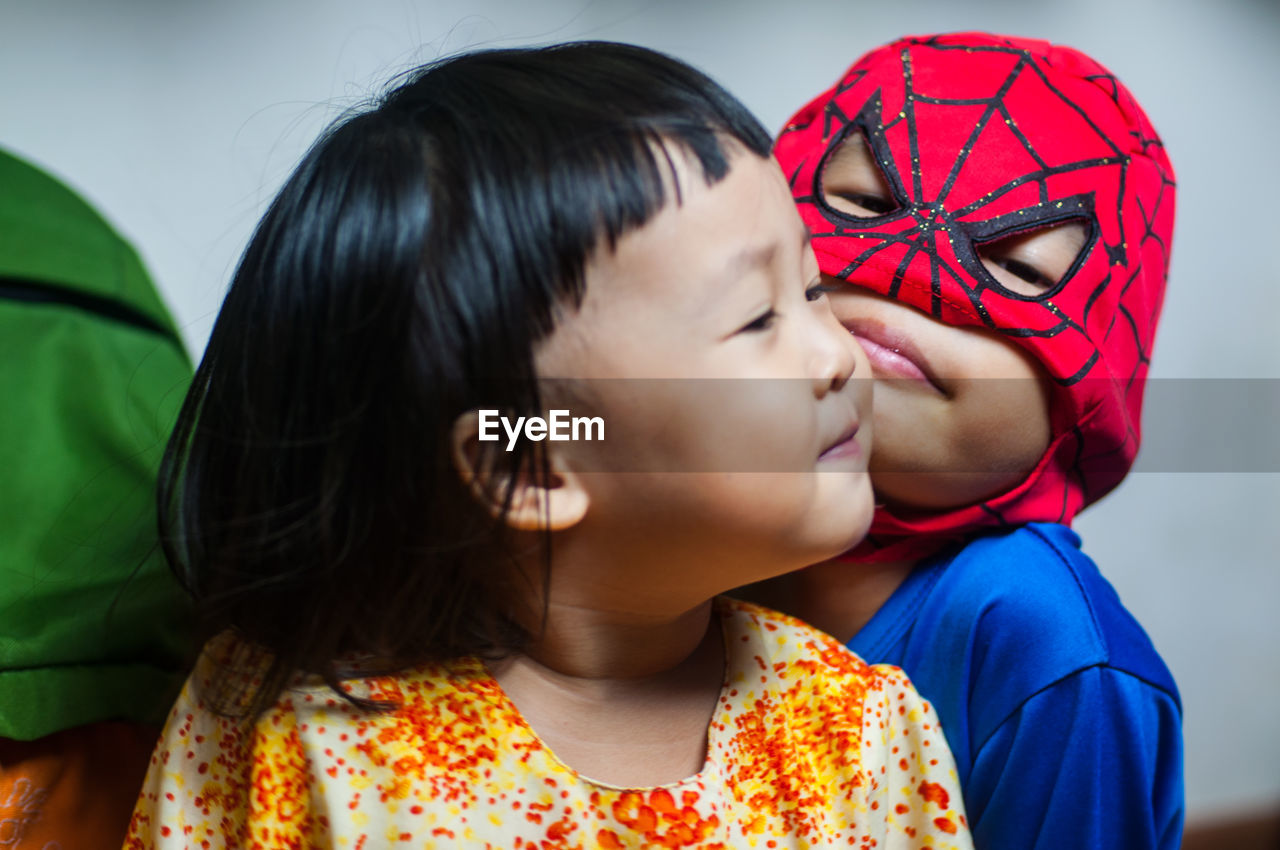 Close-up of boy in superman costume with sister at home
