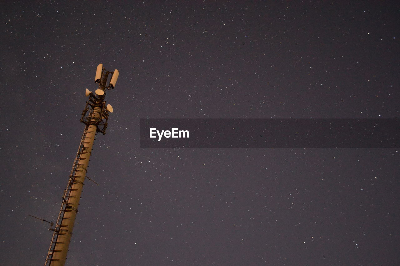 Low angle view of communications tower against star field sky at night