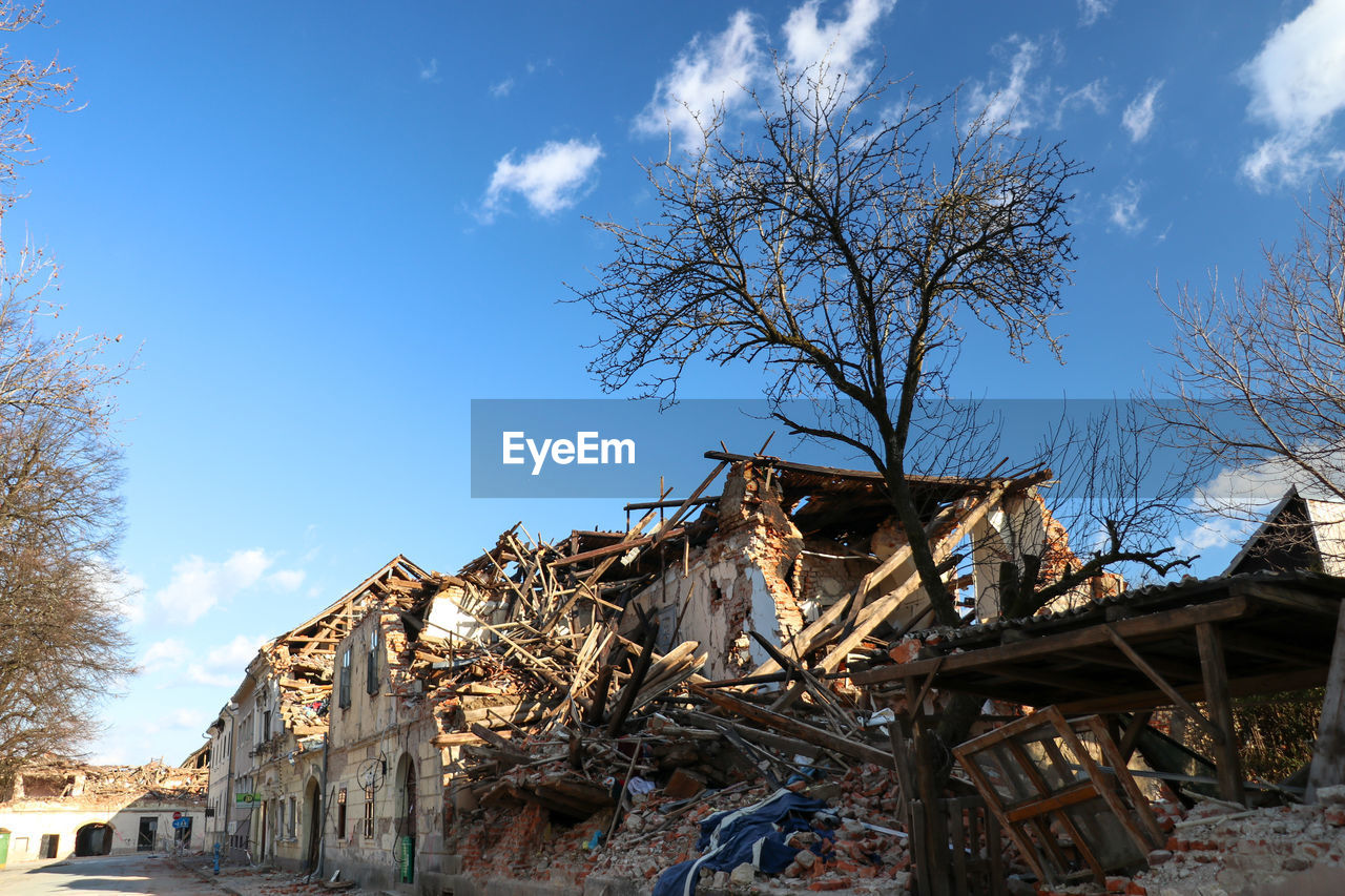 LOW ANGLE VIEW OF ABANDONED BUILDING AND BARE TREES AGAINST SKY