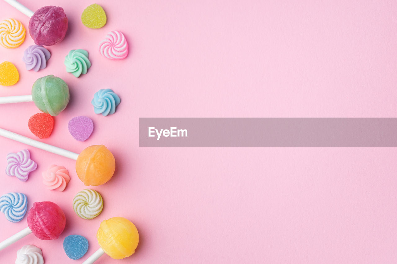 Colorful sweet lollipops and candies over pink background. flat lay, top view