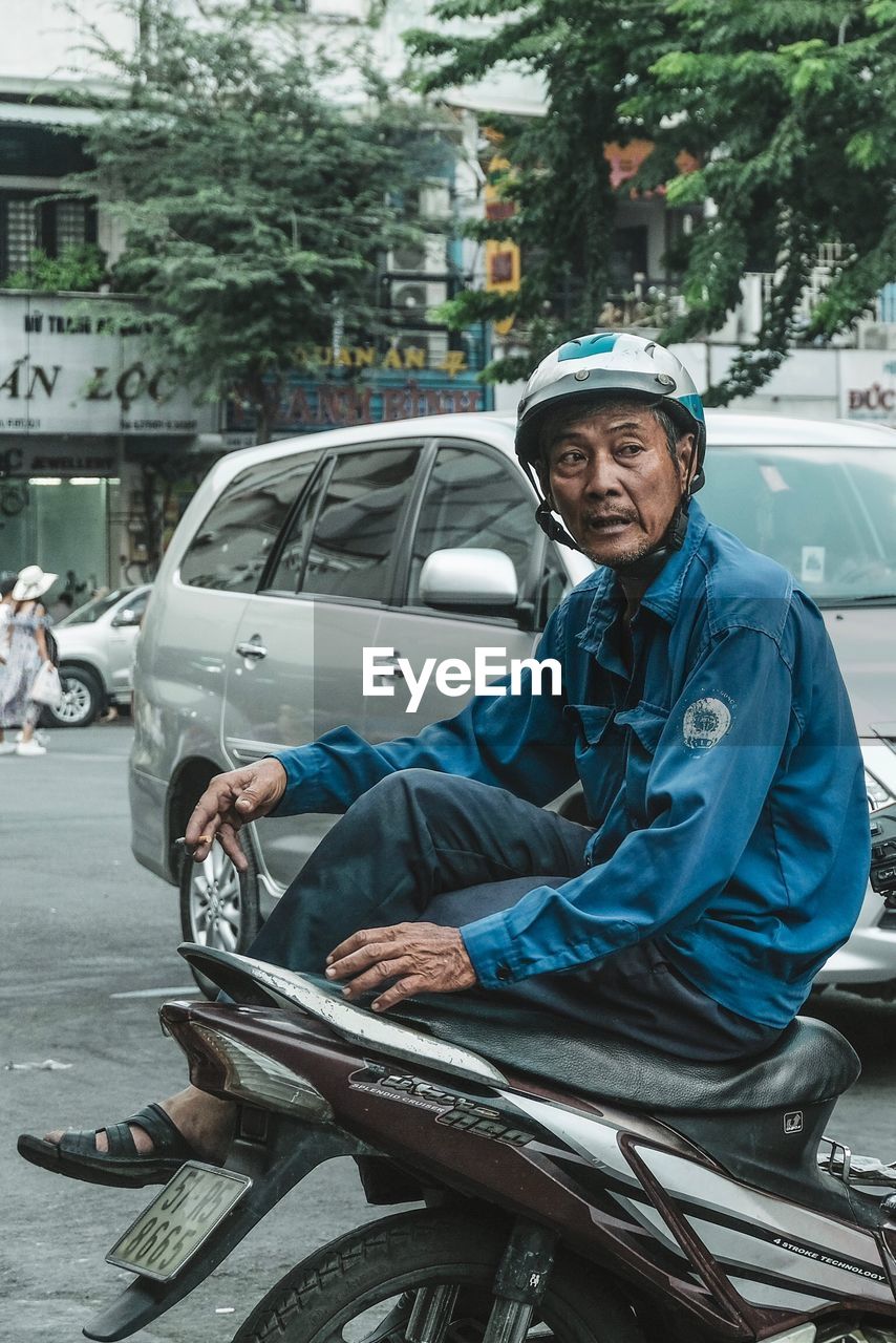 PORTRAIT OF MAN SITTING IN CAR ON ROAD