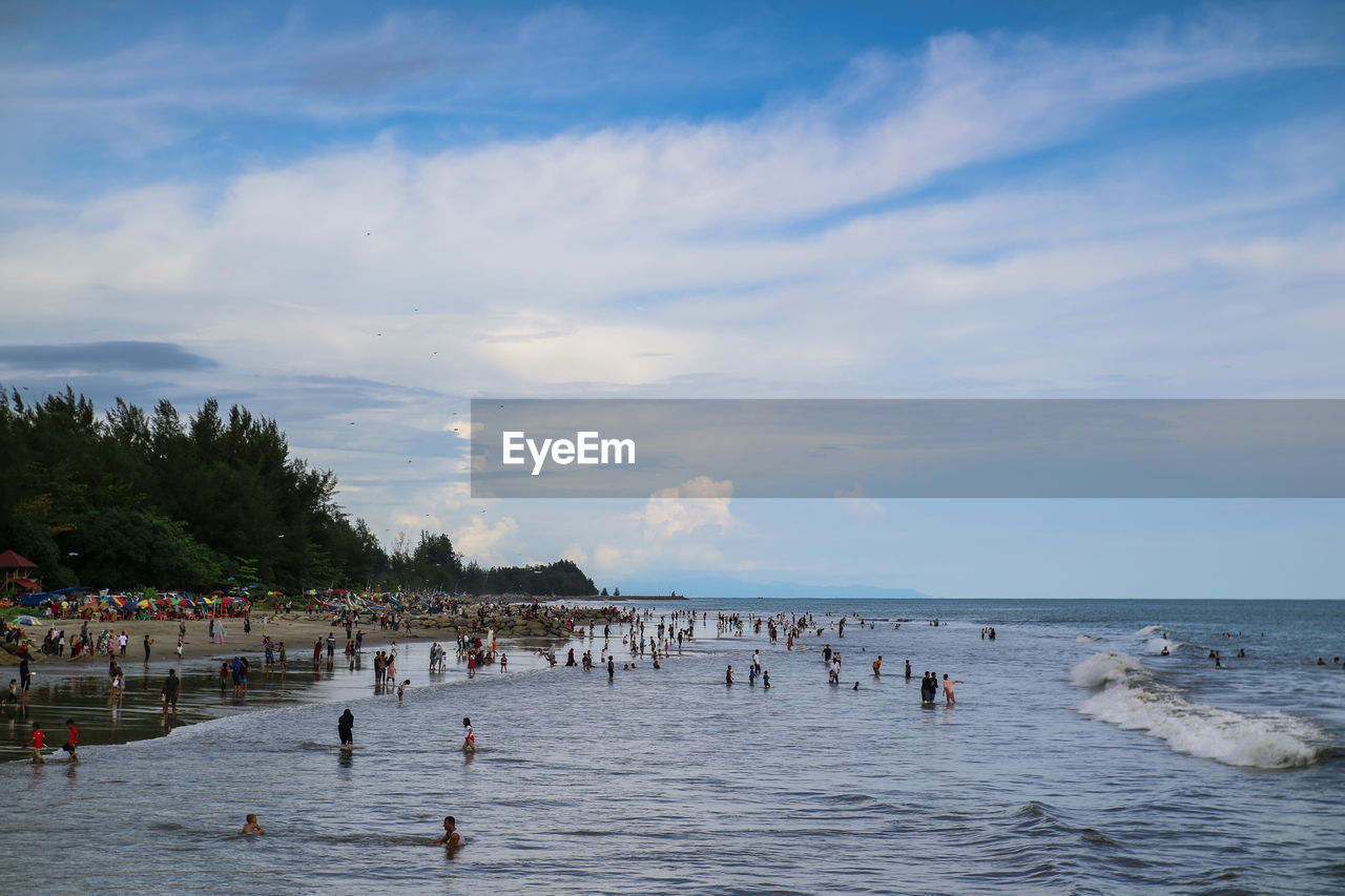 PEOPLE ON BEACH AGAINST SKY