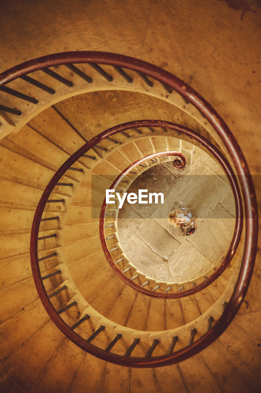 High angle view of woman standing below spiral staircase