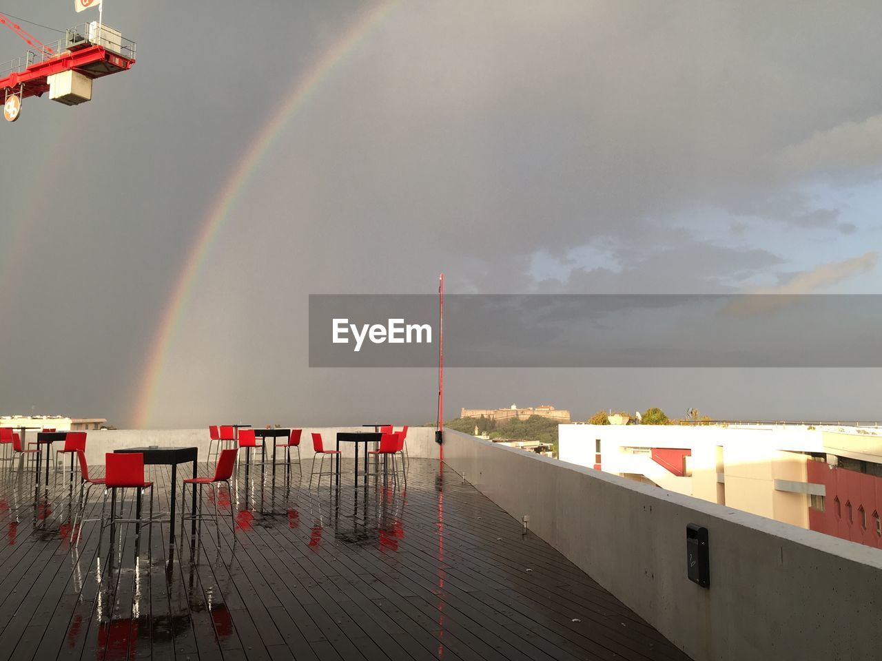 Rainbow over red seats  against sky