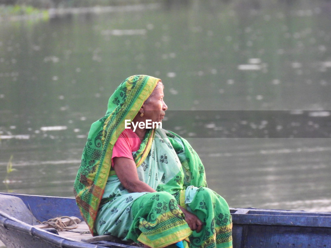 Side view of woman sitting on boat over river 