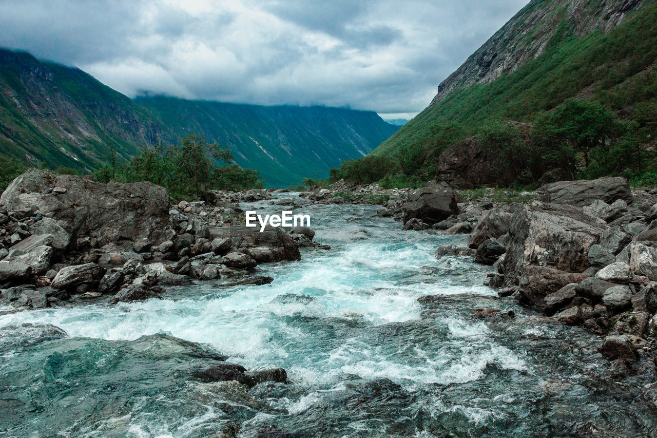 Scenic view of sea by mountains against sky