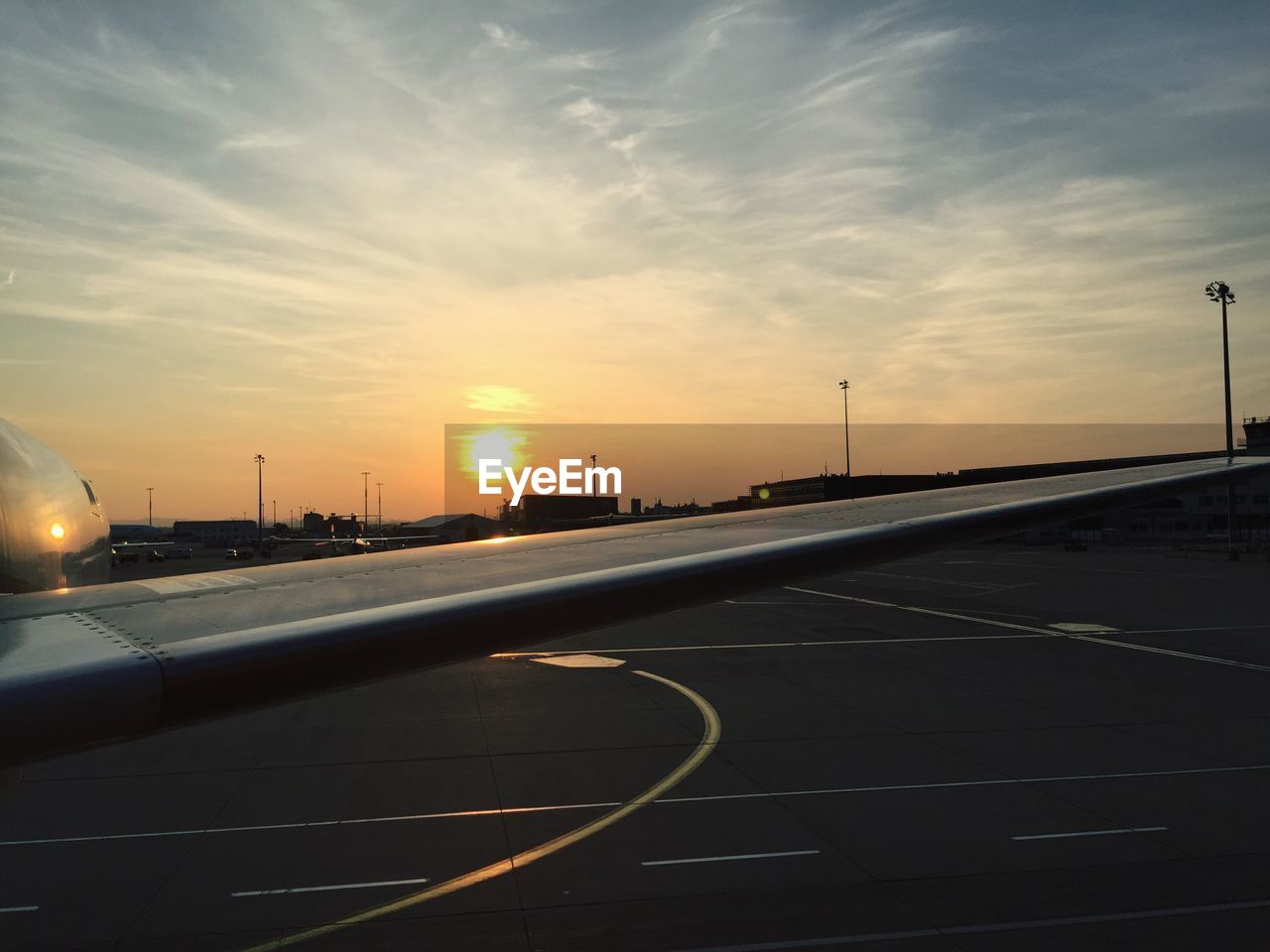Cropped image of airplane at airport against sky during sunset