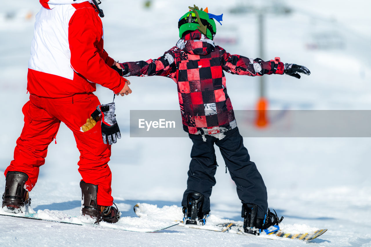 Boy learning snowboarding with an instructor