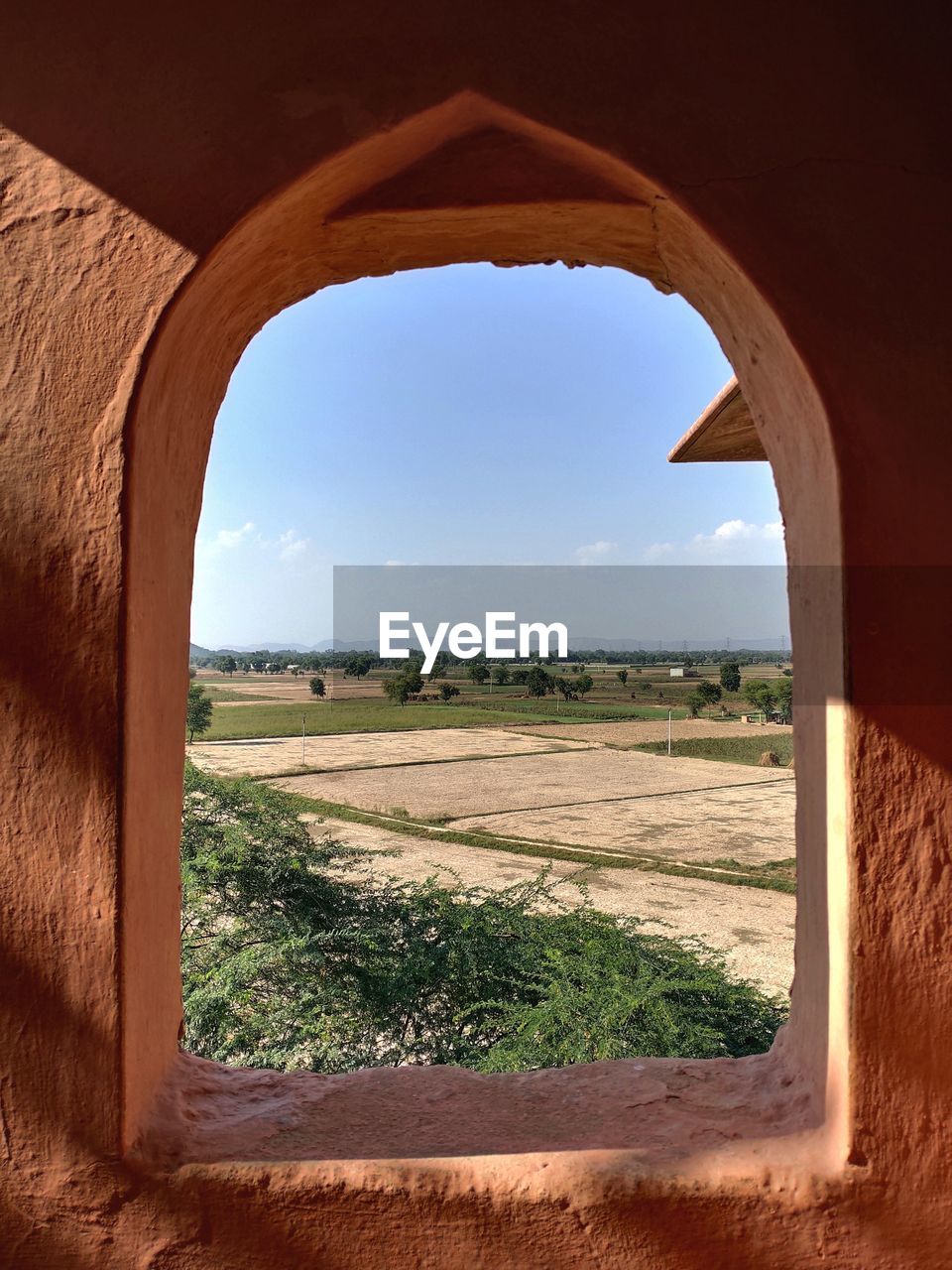 Nature theories- scenic view of field against sky seen through arched window