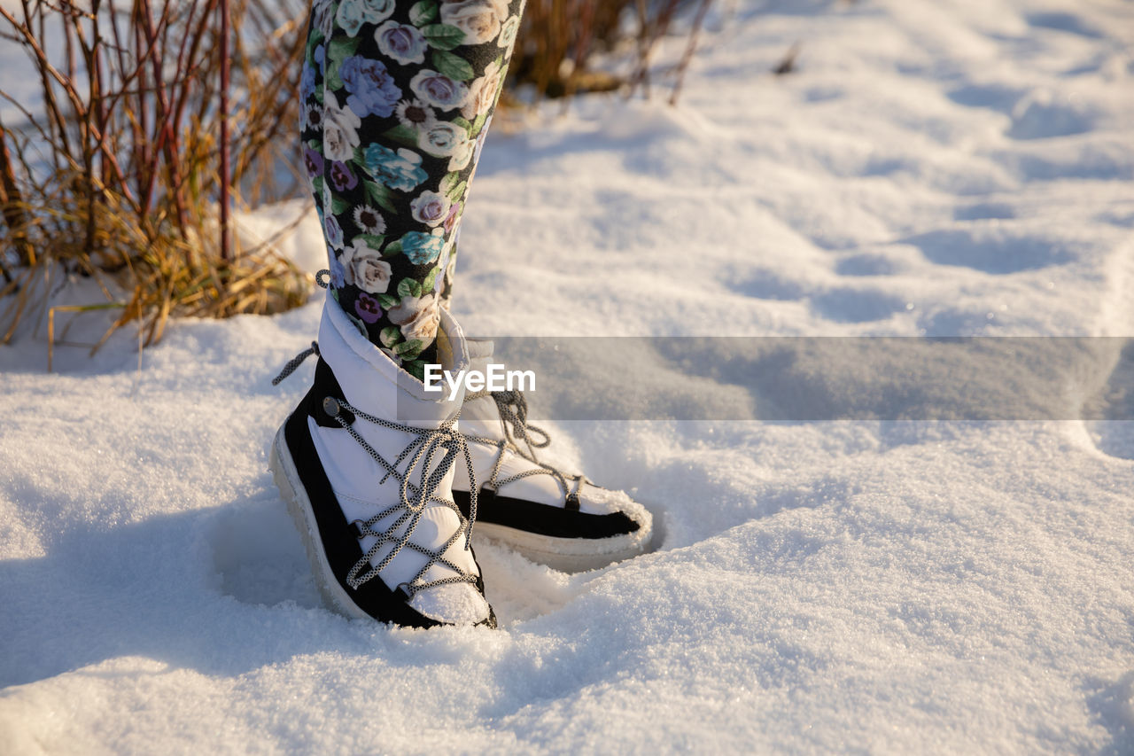 low section of woman standing on snow covered field