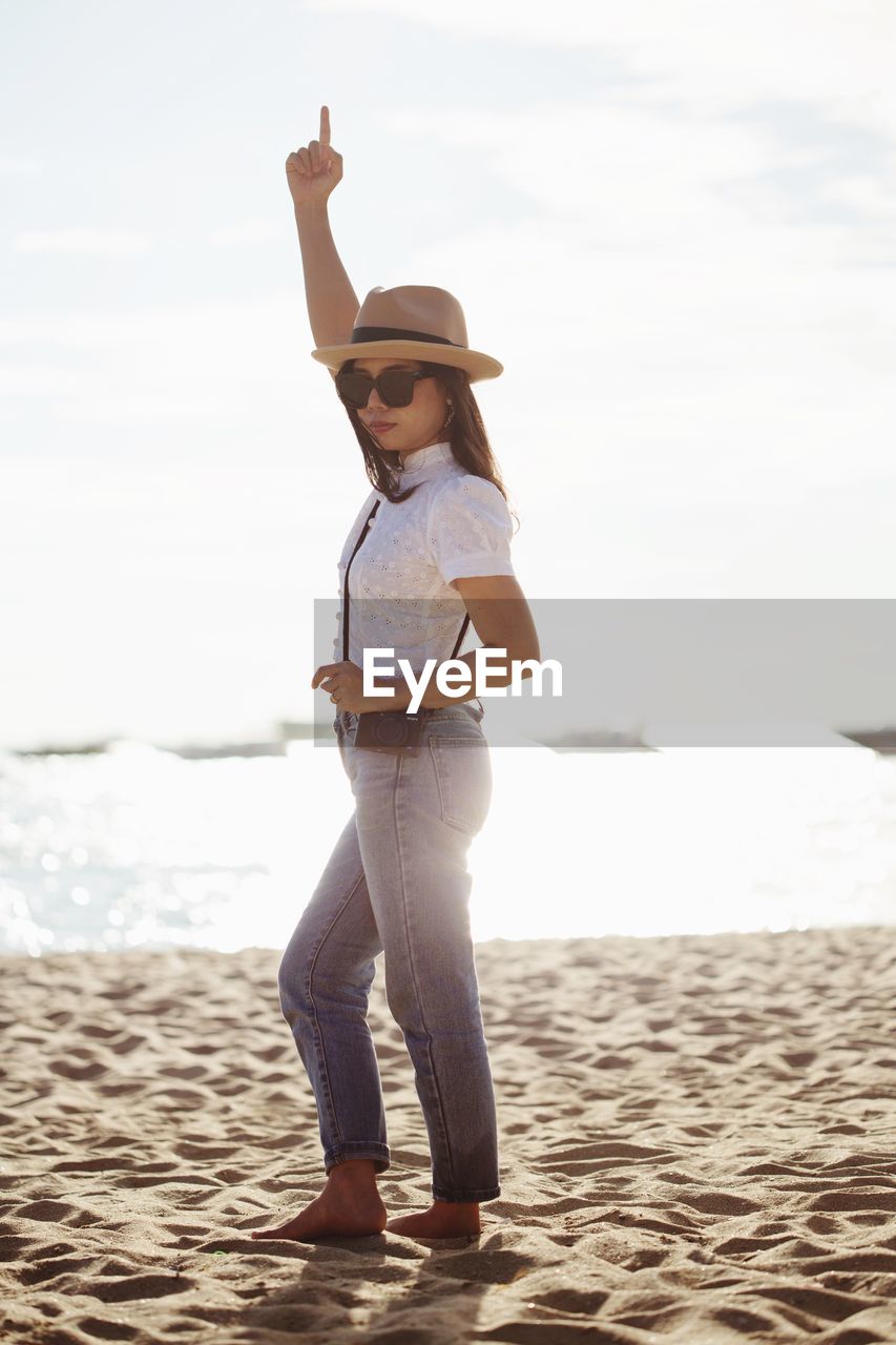 Portrait of woman wearing sunglasses while standing at beach