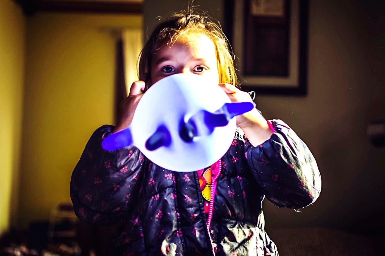 Portrait of girl blowing balloon at home