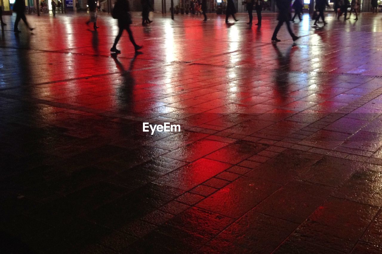 Low section of people walking on footpath at night