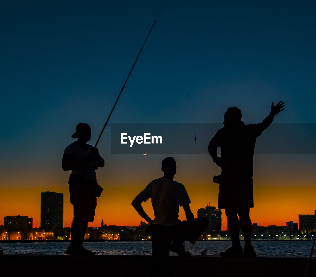 SILHOUETTE MEN FISHING AT SEA AGAINST SKY DURING SUNSET