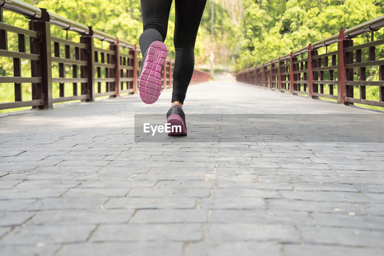 Low section of woman running on footbridge