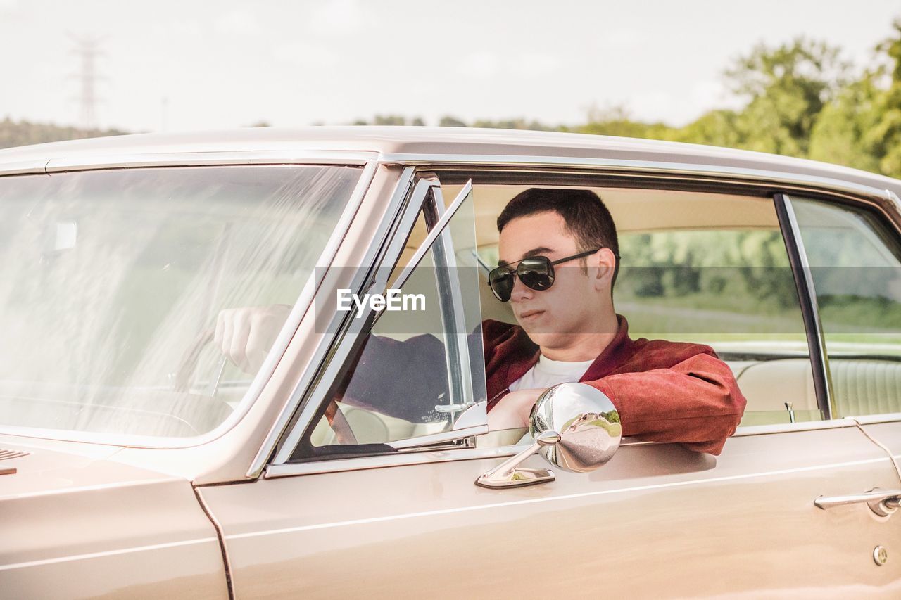 Young man wearing sunglasses while driving car