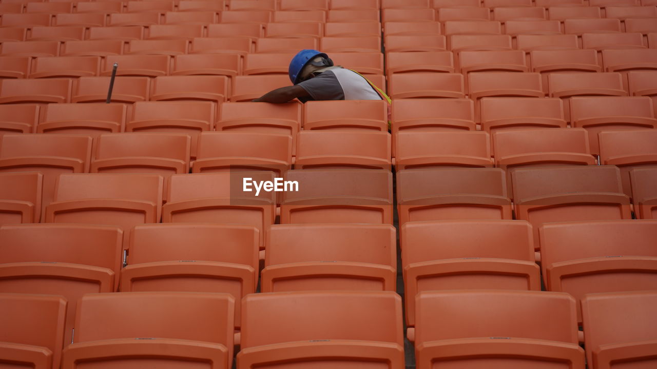 A worker between row of spectators seat in a stadium