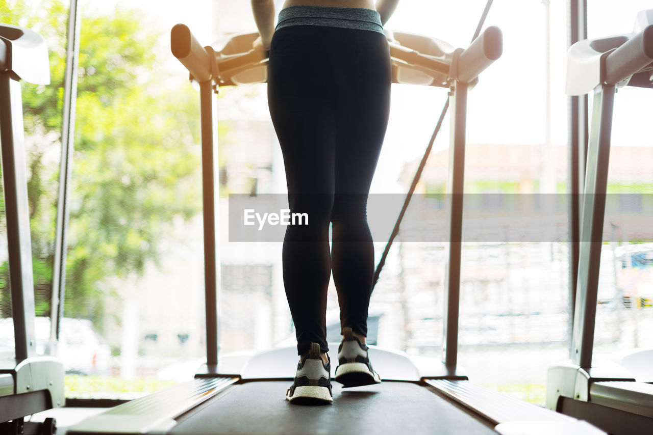 Low section of woman walking on treadmill