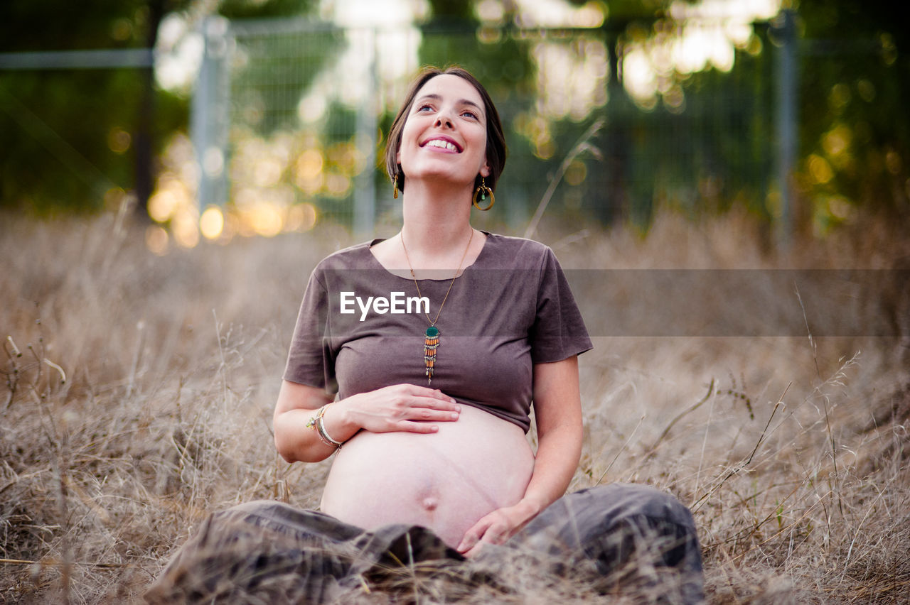 HAPPY WOMAN SITTING ON FIELD