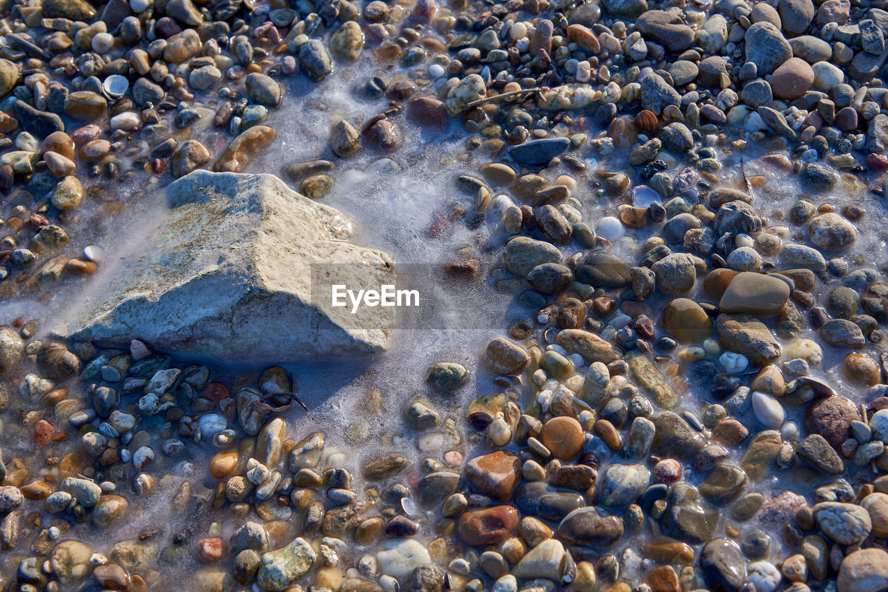 A rock and pebbels are frozen in the water from the river rhine