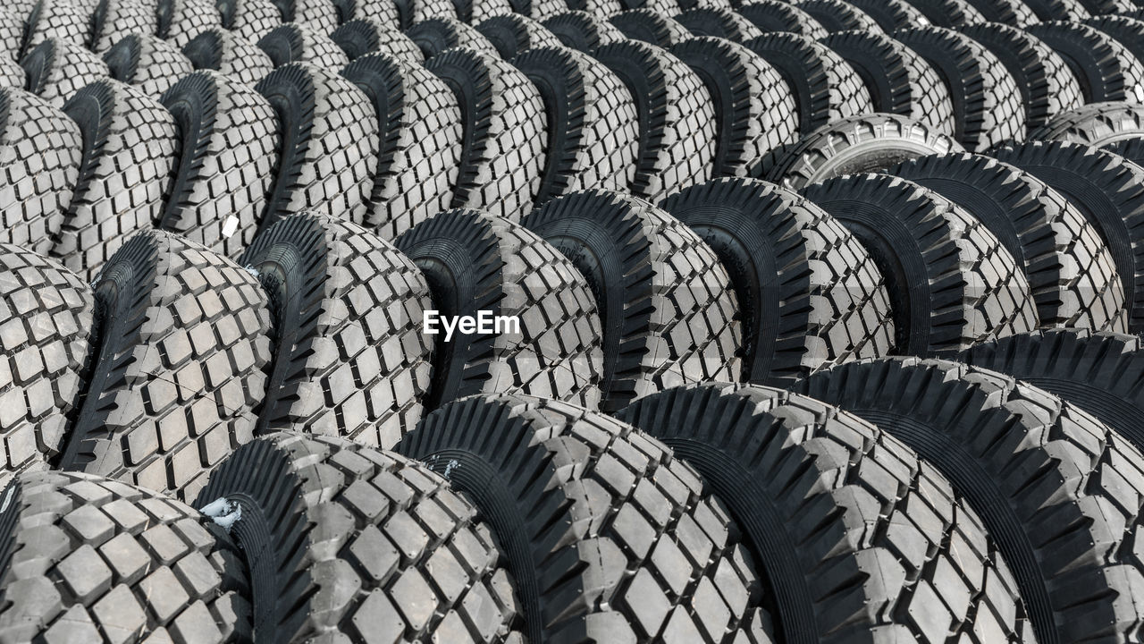 tire, tread, automotive tire, synthetic rubber, pattern, no people, large group of objects, wheel, full frame, rubber, natural rubber, in a row, backgrounds, day, arrangement, repetition, black and white, monochrome, order, outdoors, side by side, sunlight, abundance, nature, high angle view