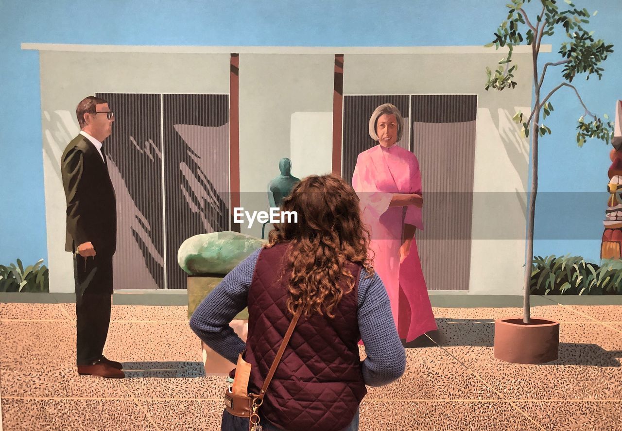 REAR VIEW OF WOMEN STANDING ON THE WALL OF A BUILDING