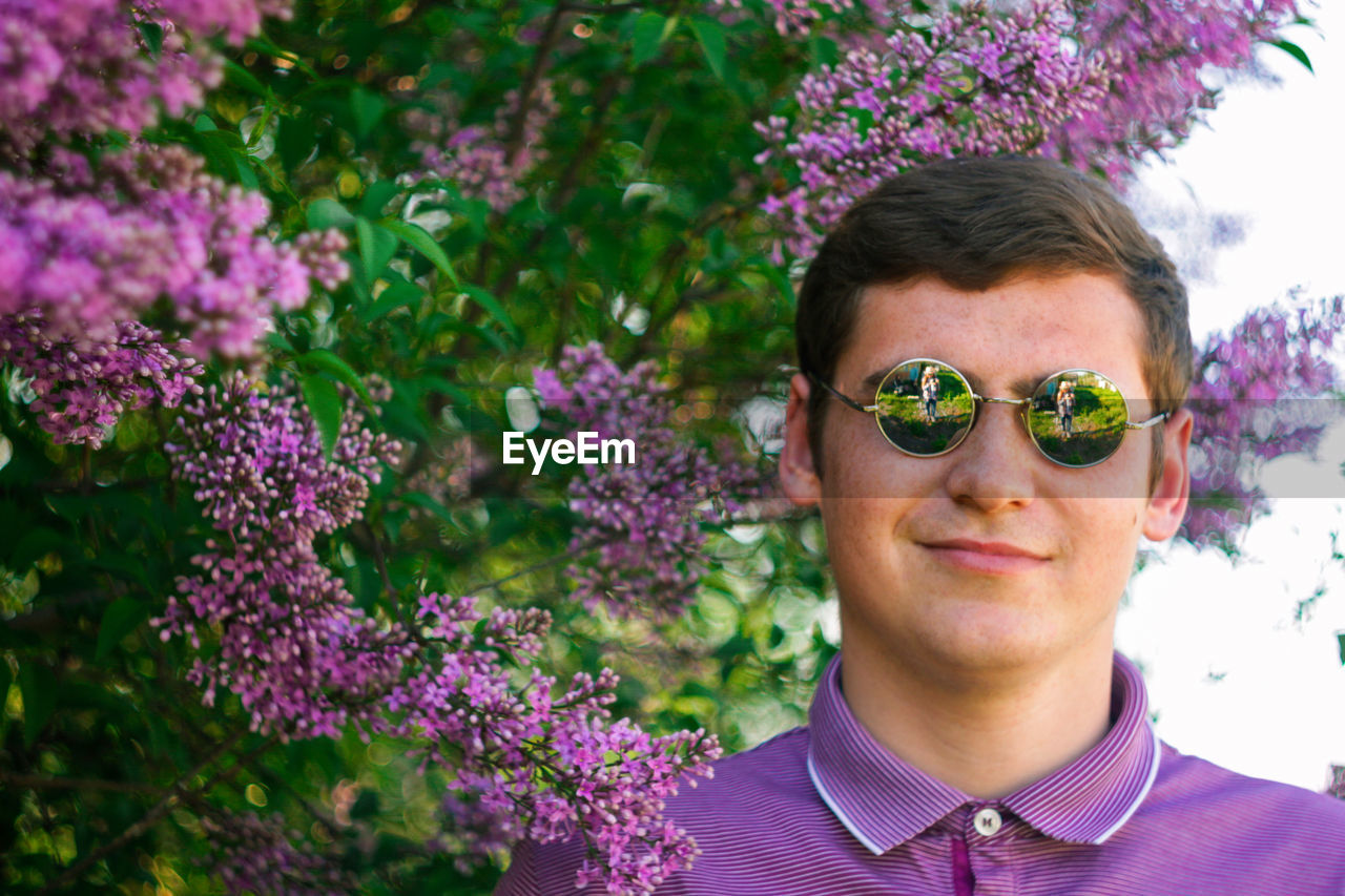 Smiling man in circle sunglasses outdoors portrait. spring people. young men in purple shirt 