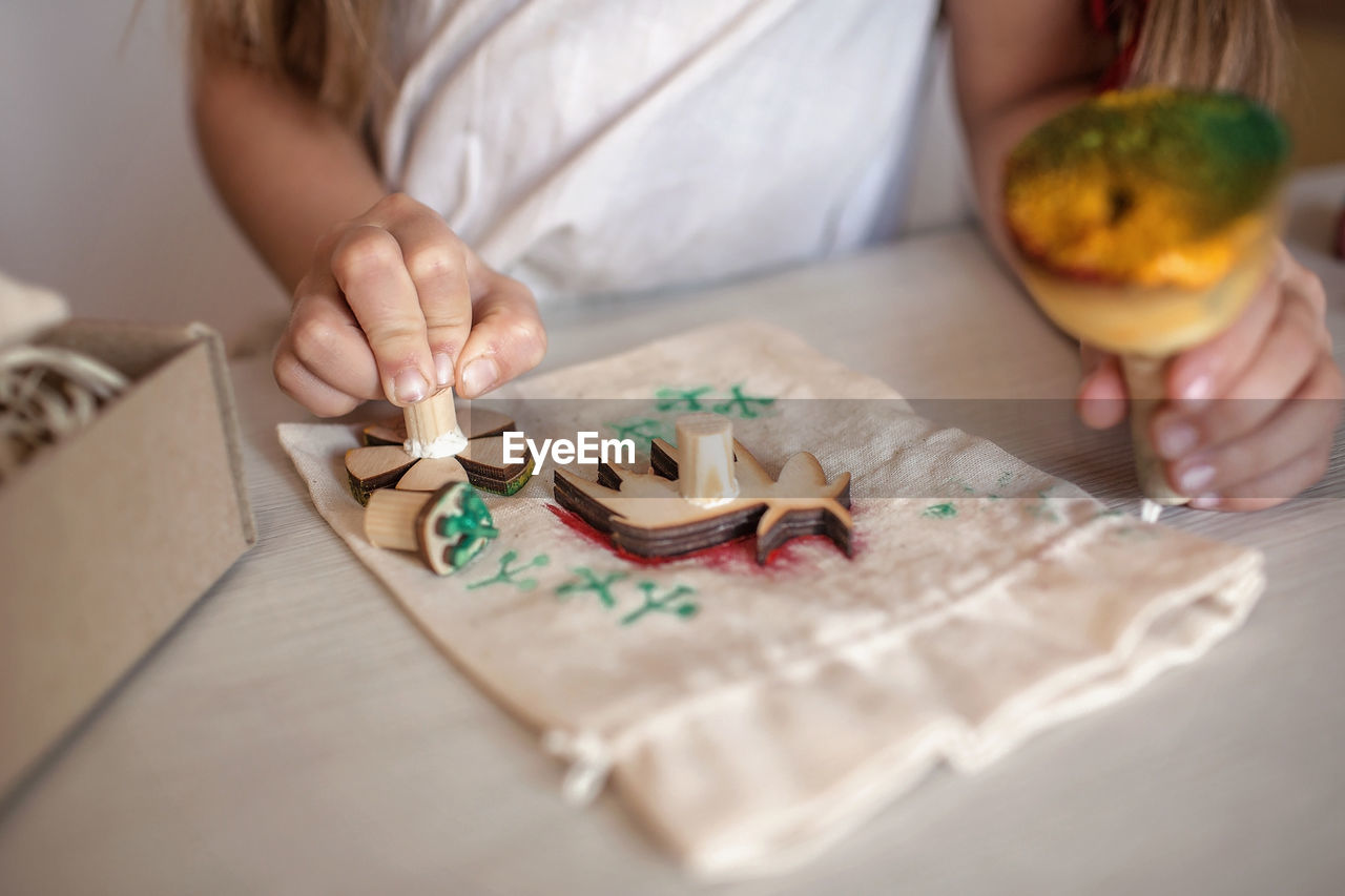 Girl doing craft wrapping for festive gifts with wooden stamp printing technique