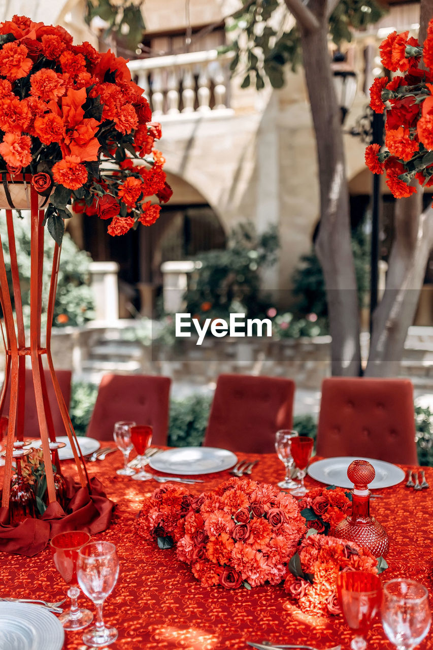 Red table wedding arrangement of roses, carnations on the background of a table with red tablecloth