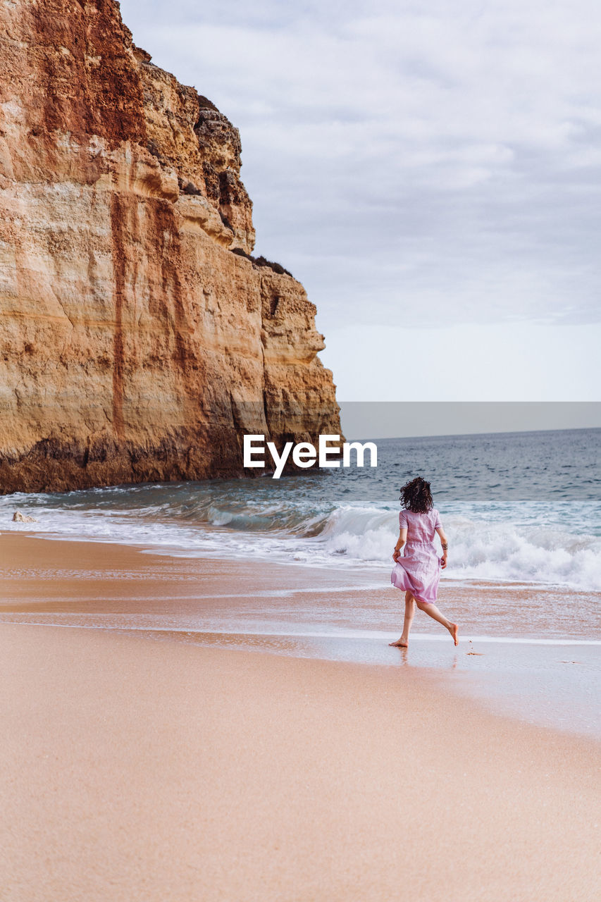 Woman standing on beach against sky