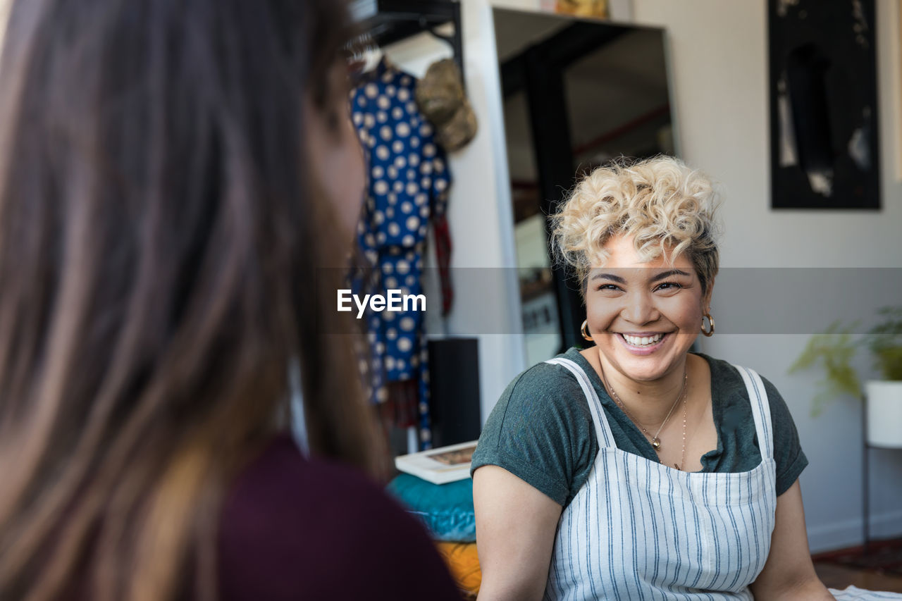 Smiling mid adult woman looking at young friend in living room