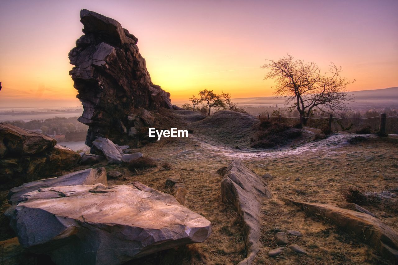 Rocks on land against sky during sunset