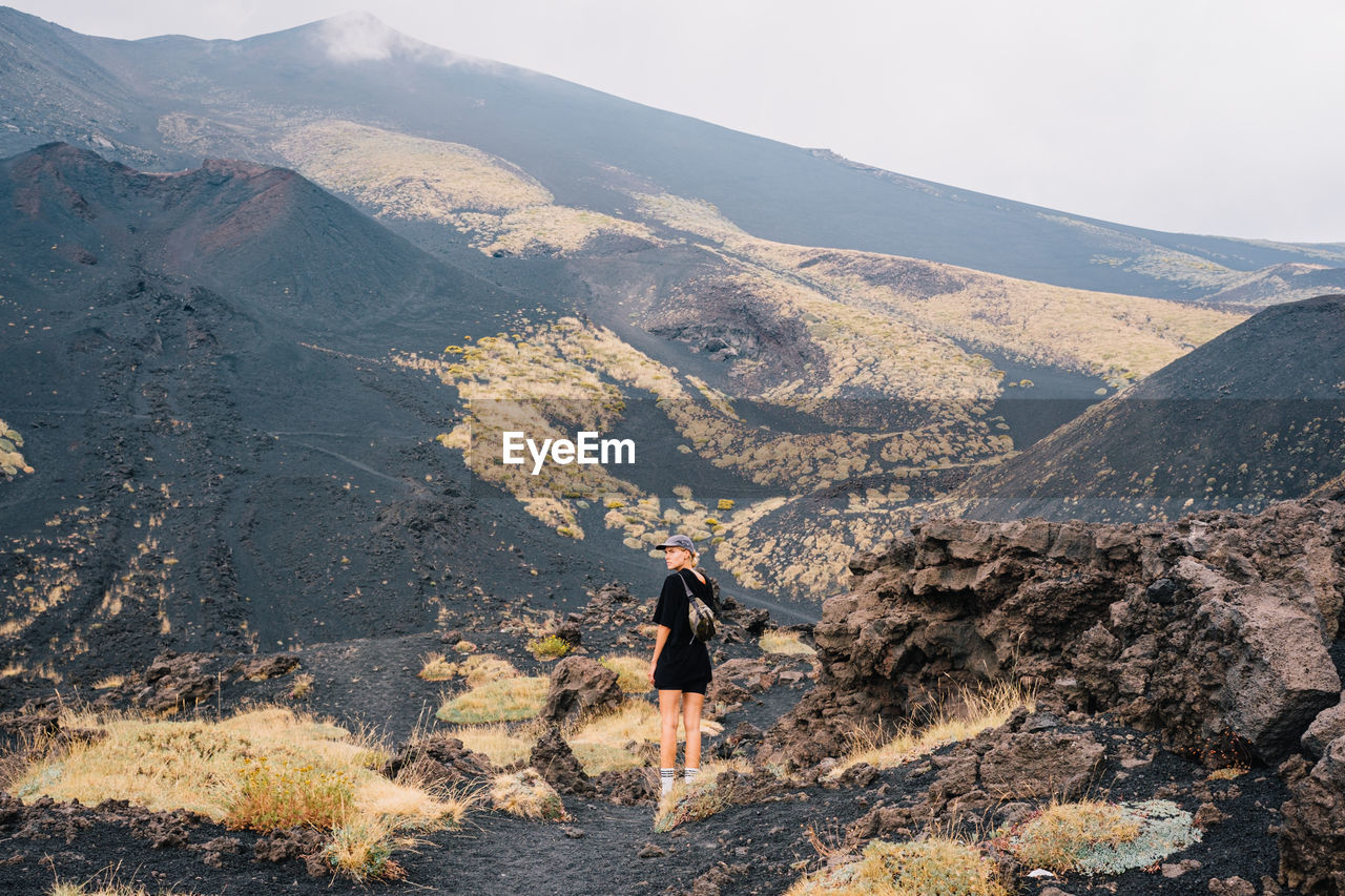 rear view of man walking on mountain against sky