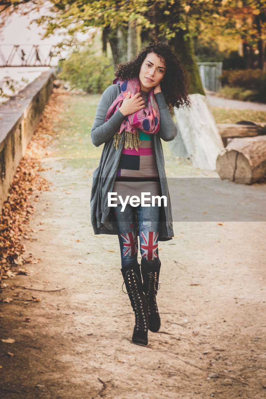 Full length portrait of young woman walking on footpath