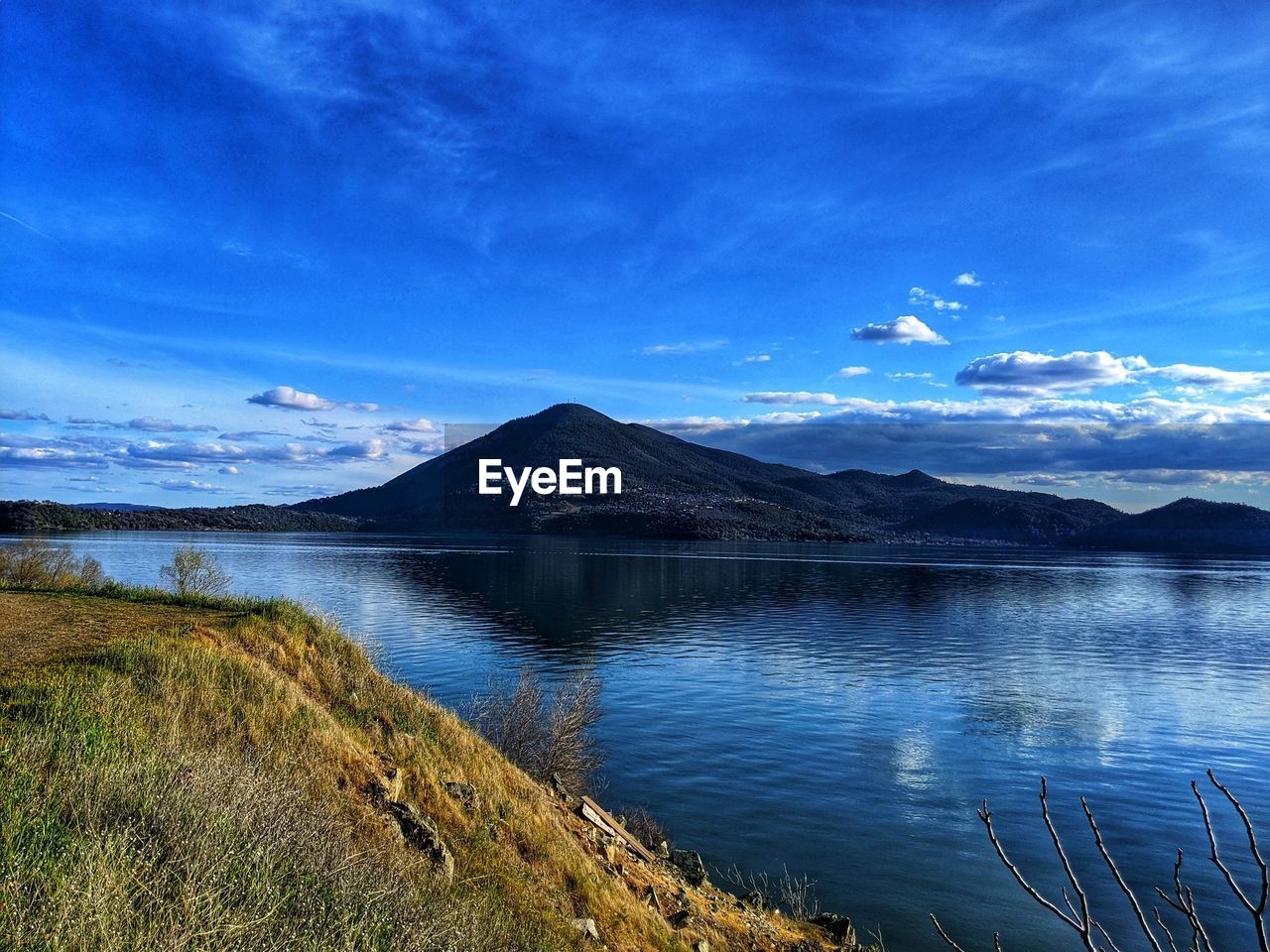 Scenic view of lake and mountains against blue sky