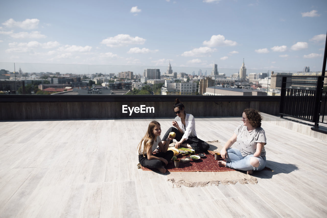 Woman with below-elbow amputation having a healthy meal on the roof with woman and girl