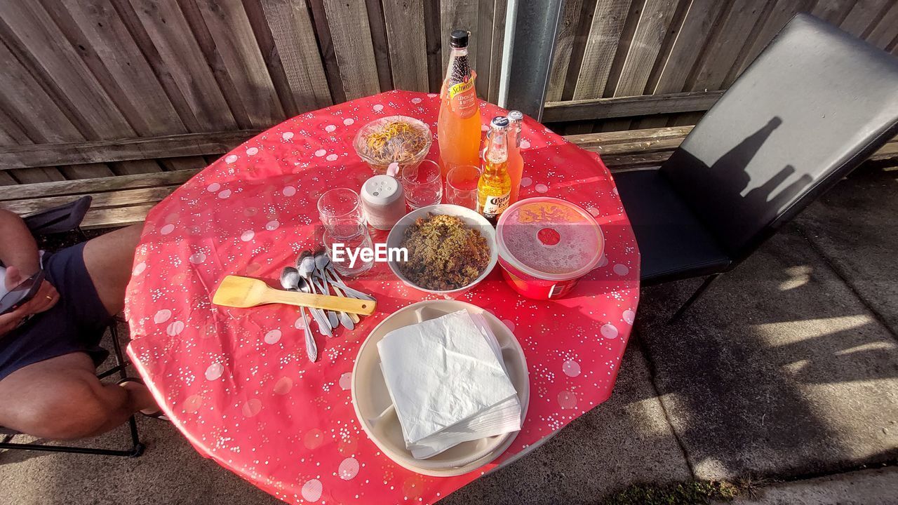 food and drink, food, high angle view, red, table, day, freshness, plate, healthy eating, clothing, fruit, nature, outdoors, sunlight, wellbeing, one person, lifestyles, meal, seat, drink, footwear, adult