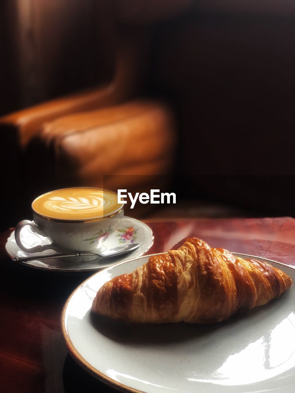 Close-up of croissant by coffee served on table
