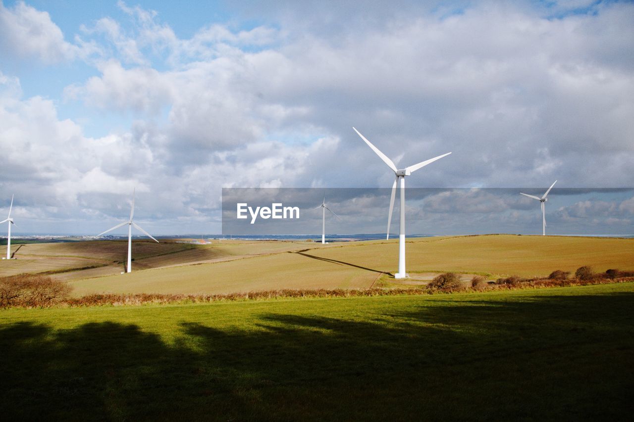 WINDMILL ON FIELD AGAINST CLOUDY SKY