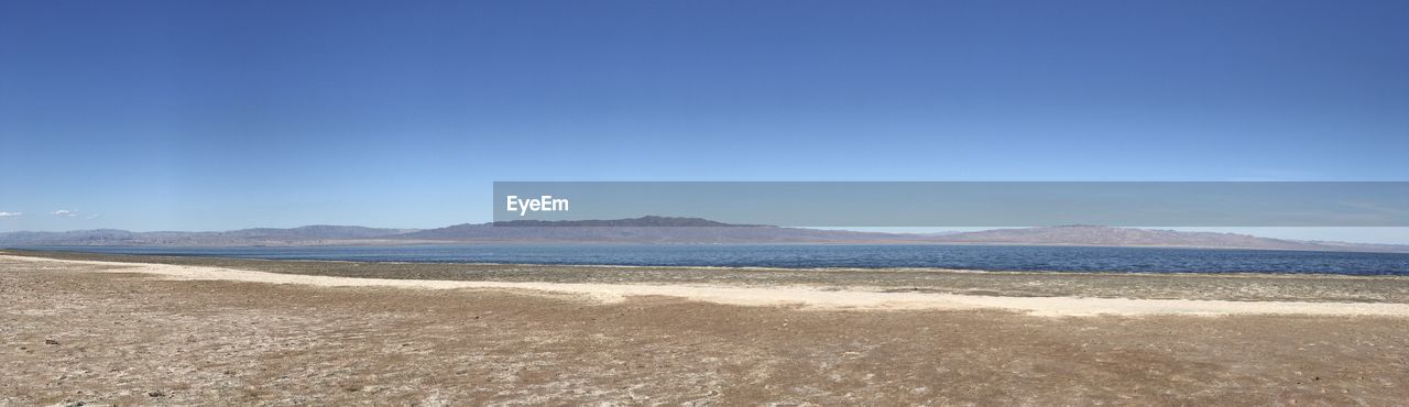 Scenic view of beach against clear blue sky