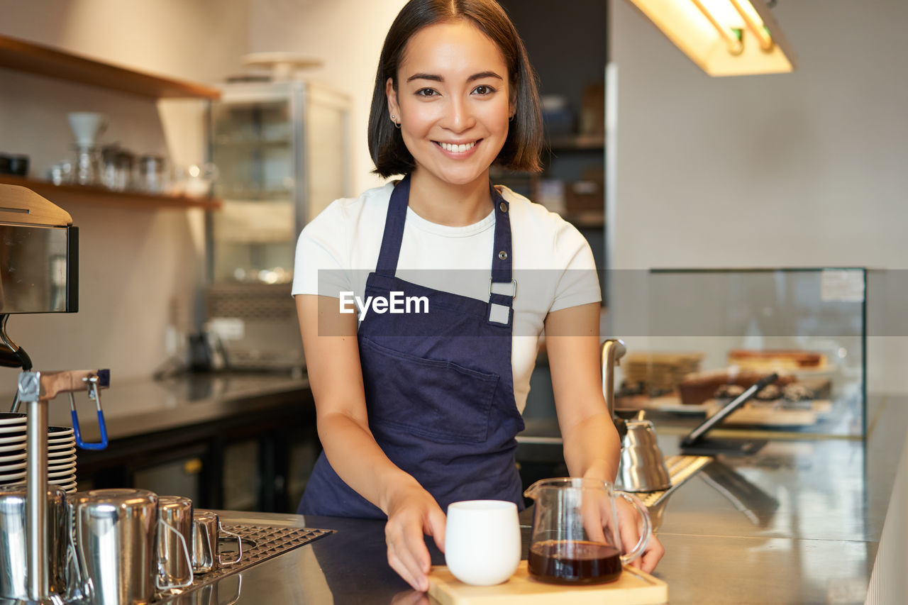 portrait of young woman standing in kitchen